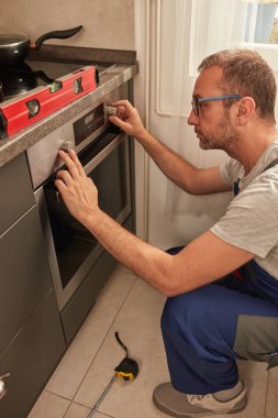 Tamirci mutfakta fırın tamir ediyor..