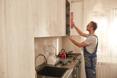 Tamirci dairedeki mutfak dolaplarını tamir ediyor..