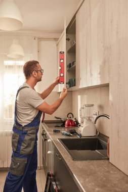 Tamirci dairedeki mutfak dolaplarını tamir ediyor..