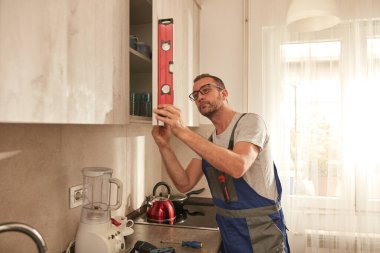 Tamirci dairedeki mutfak dolaplarını tamir ediyor..