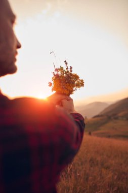 Doğada çiçekleri tutan adam.