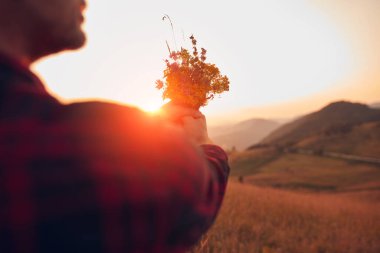 Doğada çiçekleri tutan adam.