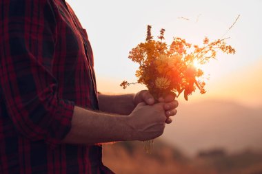 Doğada çiçekleri tutan adam.
