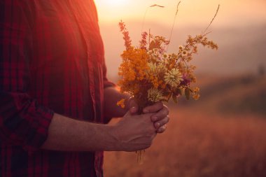 Doğada çiçekleri tutan adam.