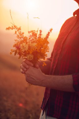 Doğada çiçekleri tutan adam.