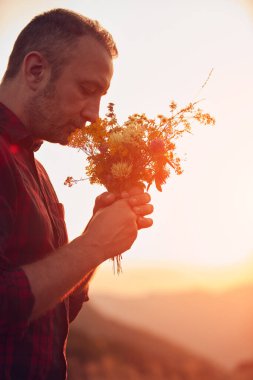 İnsan doğada çiçek toplar ve tutar..