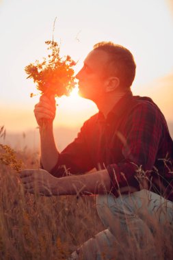 İnsan doğada çiçek toplar ve tutar..
