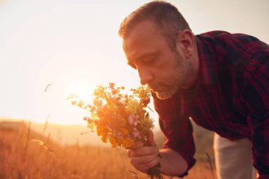 İnsan doğada çiçek toplar ve tutar..