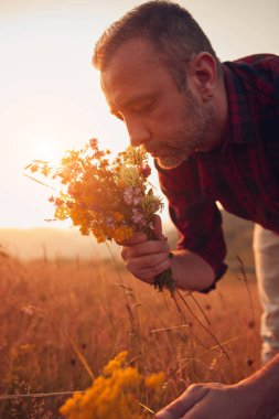 İnsan doğada çiçek toplar ve tutar..