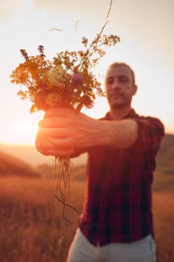 İnsan doğada çiçek toplar ve tutar..