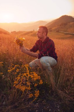 İnsan doğada çiçek toplar ve tutar..
