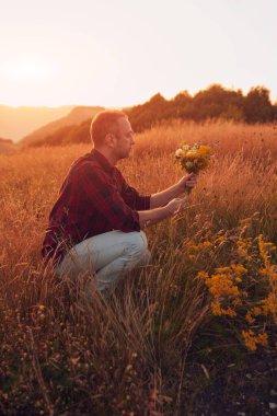 İnsan doğada çiçek toplar ve tutar..