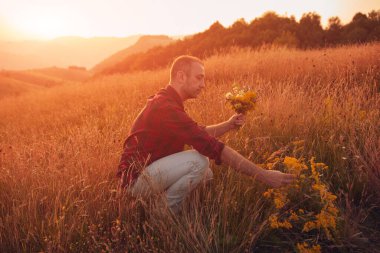 İnsan doğada çiçek toplar ve tutar..