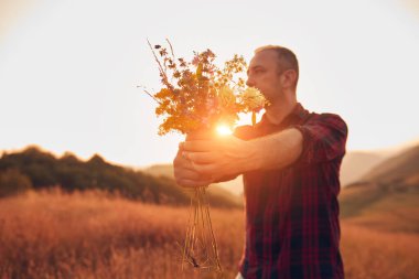 İnsan doğada çiçek toplar ve tutar..