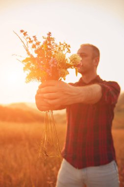 İnsan doğada çiçek toplar ve tutar..