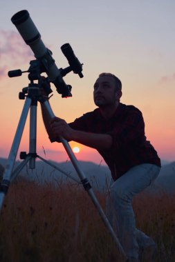 Gökyüzüne teleskopla bakan bir astronom..