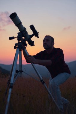 Gökyüzüne teleskopla bakan bir astronom..