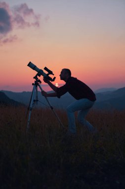 Gökyüzüne teleskopla bakan bir astronom..