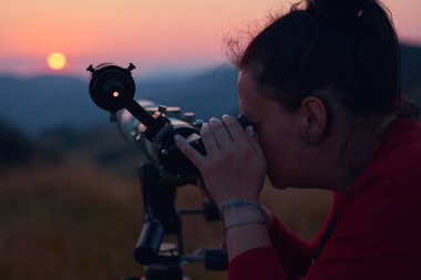 Dişi astronom teleskopla güneşe bakıyor..