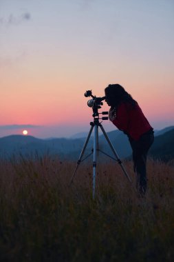 Dişi astronom teleskopla güneşe bakıyor..