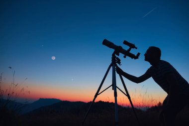 Yıldızlı gökyüzüne ve teleskopla hilal aya bakan bir astronom..