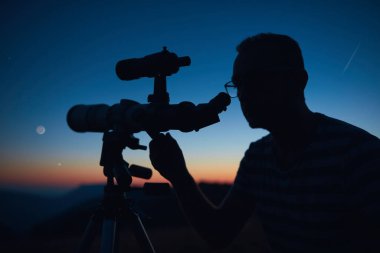 Yıldızlı gökyüzüne ve teleskopla hilal aya bakan bir astronom..