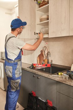 Tamirci dairedeki mutfak dolaplarını tamir ediyor..