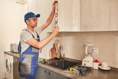 Tamirci dairedeki mutfak dolaplarını tamir ediyor..