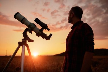 Gökyüzüne teleskopla bakan bir astronom..