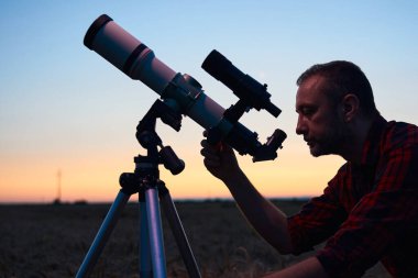 Gökbilimci teleskopla gece gökyüzüne bakıyor..