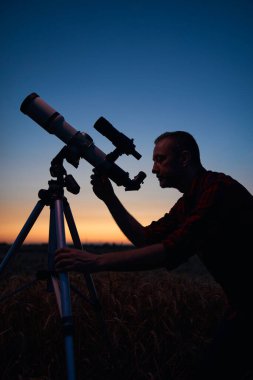 Gökbilimci teleskopla gece gökyüzüne bakıyor..