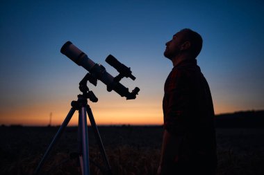 Gökbilimci teleskopla gece gökyüzüne bakıyor..
