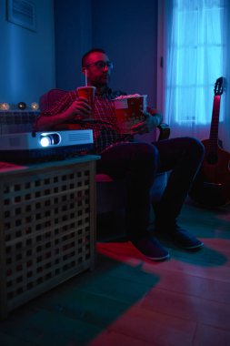 Adam evde film izlerken patlamış mısır ve meyve suyu içiyor..