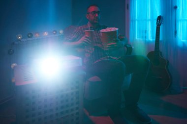 Adam evde film izlerken patlamış mısır ve meyve suyu içiyor..