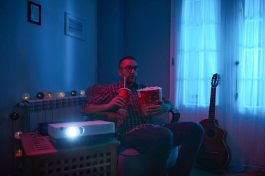 Adam evde film izlerken patlamış mısır ve meyve suyu içiyor..