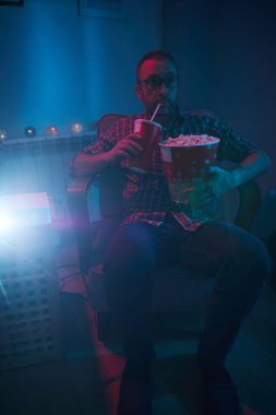 Adam evde film izlerken patlamış mısır ve meyve suyu içiyor..