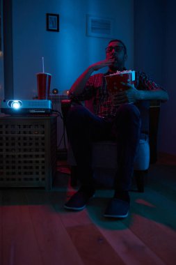 Adam evde film izlerken patlamış mısır ve meyve suyu içiyor..
