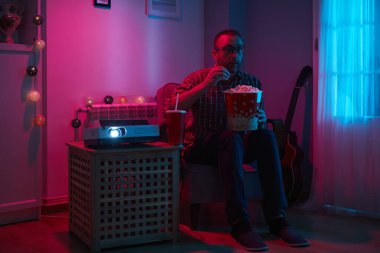 Adam evde film izlerken patlamış mısır ve meyve suyu içiyor..