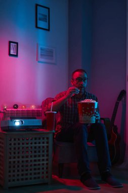 Adam evde film izlerken patlamış mısır ve meyve suyu içiyor..