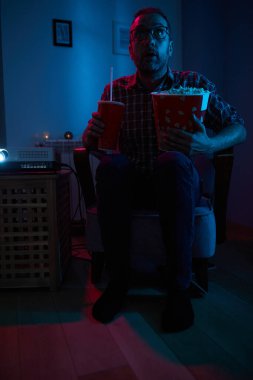 Adam evde film izlerken patlamış mısır ve meyve suyu içiyor..