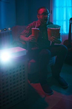 Adam evde film izlerken patlamış mısır ve meyve suyu içiyor..