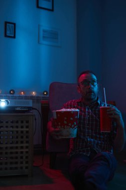 Adam evde film izlerken patlamış mısır ve meyve suyu içiyor..