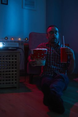 Adam evde film izlerken patlamış mısır ve meyve suyu içiyor..
