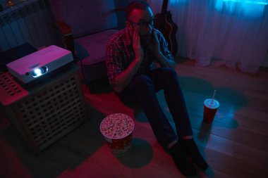 Adam evde film izlerken patlamış mısır ve meyve suyu içiyor..