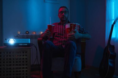 Adam evde film izlerken patlamış mısır ve meyve suyu içiyor..