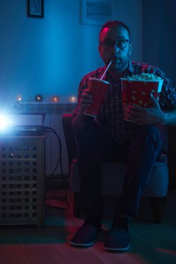 Adam evde film izlerken patlamış mısır ve meyve suyu içiyor..