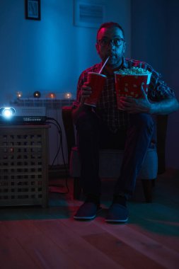 Adam evde film izlerken patlamış mısır ve meyve suyu içiyor..