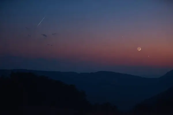 stock image Silhouette of a countryside with Milky Way stars, shooting star, planets and crescent Moon.