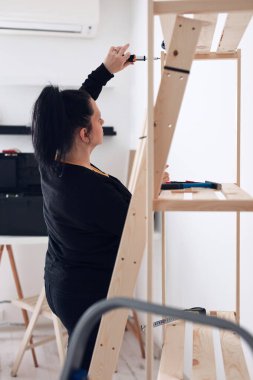 Yeni ahşap raf ve mobilyaları bir araya getiren kadın..