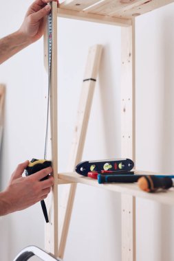 Yeni ahşap bir raf ve mobilya monte eden bir adam..